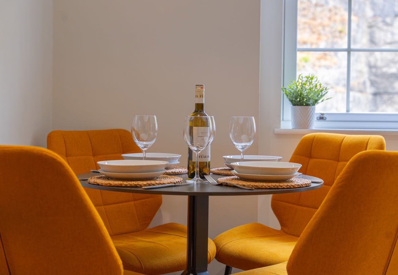 Image of a black dining table and 4 mustard yellow chairs in apartment 41